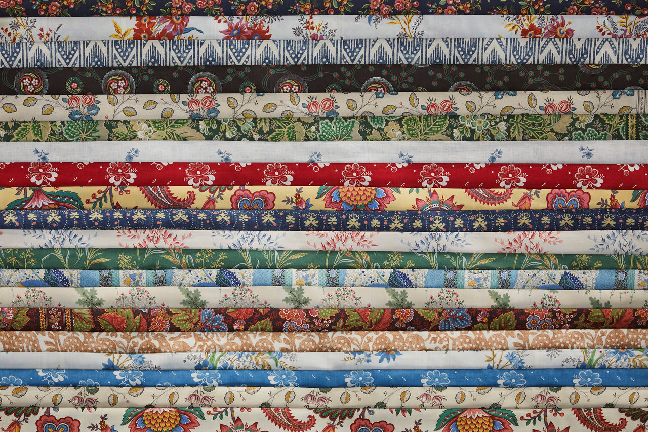 Stack of Décors Barbares fabric swatches in floral, ikat, paisley, and colorways like cream, yellow, blue, burgundy.