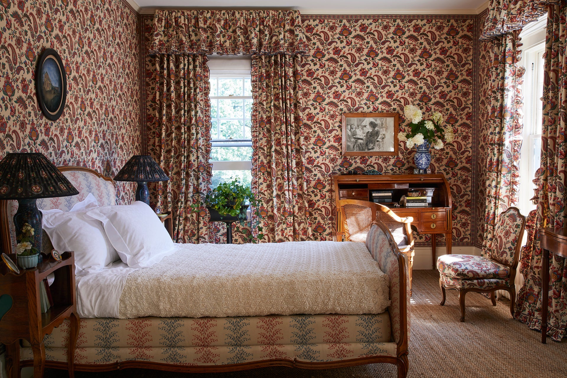 Décors Barbares fabrics cover all surfaces of a bedroom, including the bed frame, wallpaper, lampshade, curtains and upholstered chair.