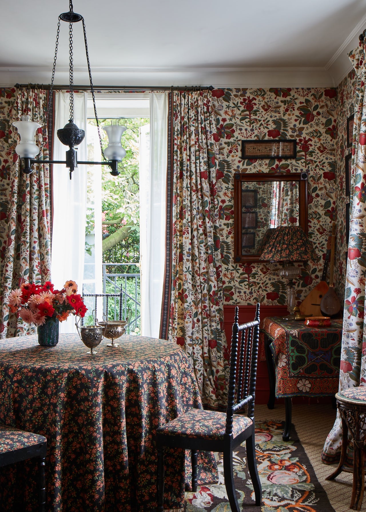 Dining room with Décors Barbares Koubla wallpaper and fabric curtains and chairs upholstered in navy Sarafane fabric with a matching tablecloth.
